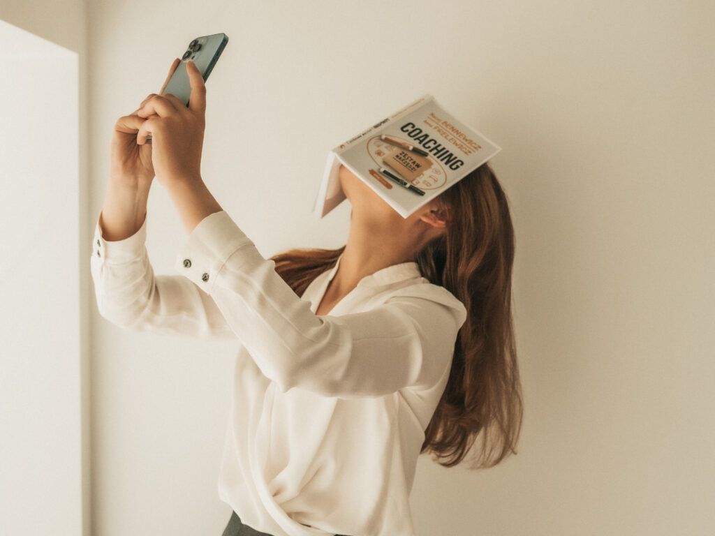 kobieta trzyma nowe technologie i książkę coaching